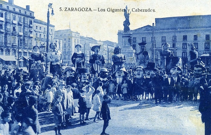 Tarjeta de la decada de los años 30 del siglo pasado, con los Gigantes y cabezudos mezclados con niños y mayores en la plaza central de la ciudad